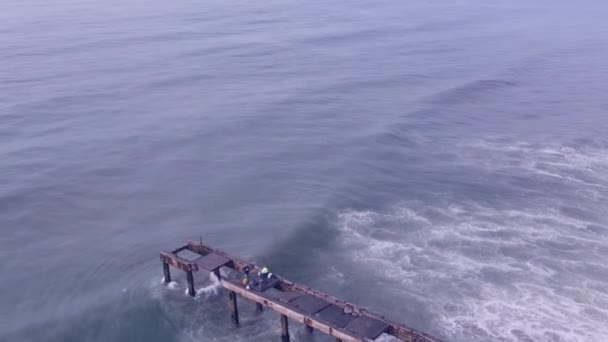 Dron latający nad oceanem ze starym molo widzianym poniżej — Wideo stockowe