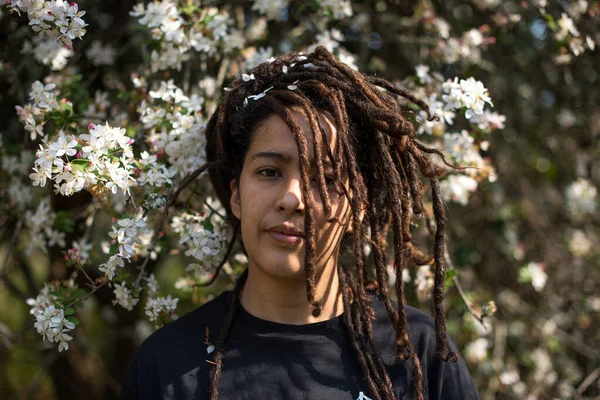 Portrait de femme avec des sauterelles debout contre un arbre en fleurs — Photo