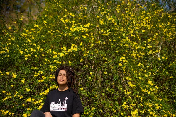 Porträt einer Frau, die gegen blühende Pflanzen sitzt — Stockfoto
