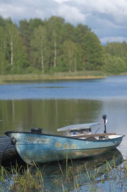 Gölün rıhtımındaki düz tabanlı mavi tekne, güneş enerjili motorlu.