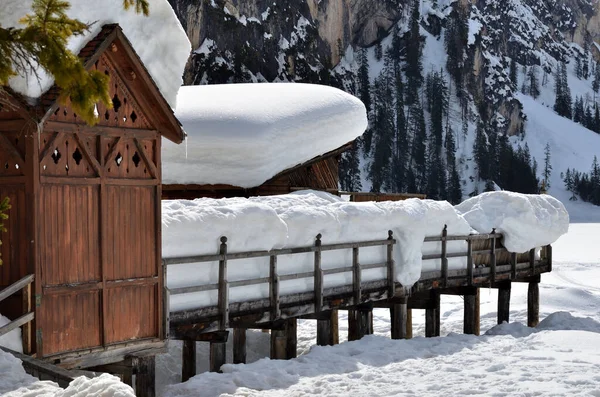 The old wooden structure of the boat rental on Lake Braies covered by a heavy snowfall