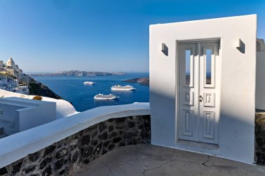 Turistler, Ege Denizi 'nin ikonik beyaz mimarisinin ve çarpıcı manzarasının keyfini çıkarırken, Yunanistan' ın Santorini kentindeki kalderaya demirlemiş seyir gemileri görülüyor..