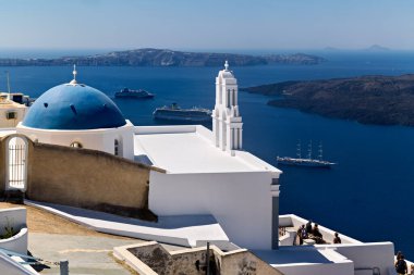 Yunanistan 'ın Santorini kentindeki ikonik kalderanın tadını çıkaran turistler, Ege Denizi' ndeki yolcu gemilerine tepeden bakan geleneksel beyaz ve mavi binalara sahipler..