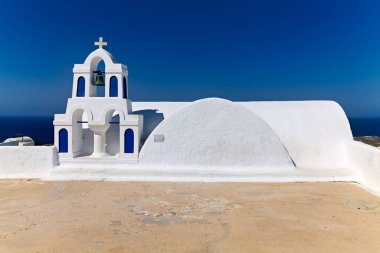 Çan kulesi ve açık mavi gökyüzünün altında Ege Denizi 'ne bakan mavi aksanlı geleneksel bir Yunan Ortodoks kilisesi. Yunan adasında kutsal bir yer.