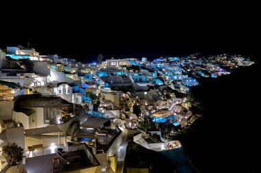 Yunanistan 'ın Santorini kentindeki aydınlık kayalık köy Oia' nın muhteşem gece manzarası ikonik beyaz binalarını ve mavi aksanlarını gözler önüne seriyor..