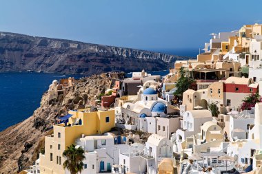 Turistler, ikonik beyaz ve mavi mimari ve çarpıcı Ege Denizi manzaralarına hayran kalarak, Yunanistan 'ın Santorini kentindeki kayalık bir köy olan Oia' yı keşfediyorlar..