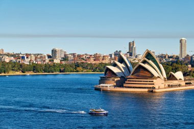Avustralya 'daki ikonik Sydney Opera Binası' nın önünden feribot mavi sularda yüzüyor..