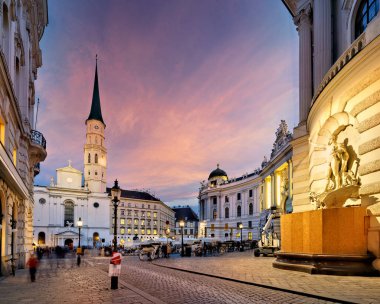 Michaelerplatz Viyana, Avusturya 'da, alacakaranlıkta, St. Michael Kilisesi, Hofburg Sarayı ve at arabalarıyla. Turistler tarihi kentin tadını çıkarıyor.