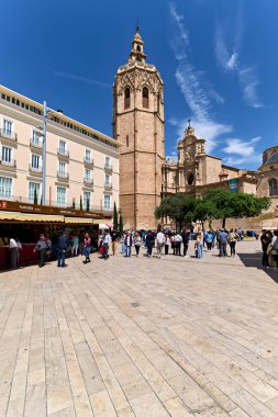 Ziyaretçiler açık bir gökyüzünün altındaki plazadaki Valencia Katedrali 'nin önünde toplandılar. İnsanlar yürür ve mimariye hayran kalırlar..