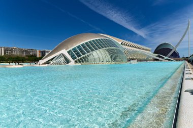Ziyaretçiler Hemisferic yakınlarındaki Valencia 'daki Sanat ve Bilim Şehri' ni keşfediyorlar. Berrak sular, mavi gökyüzünün altındaki modern mimariyi yansıtıyor..