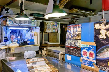 Bir satıcı Tokyo 'da bir balık pazarında çalışıyor. Taze deniz ürünleri tezgahta sergilenir. Müşteriler yakınlarda geziniyor olabilir..