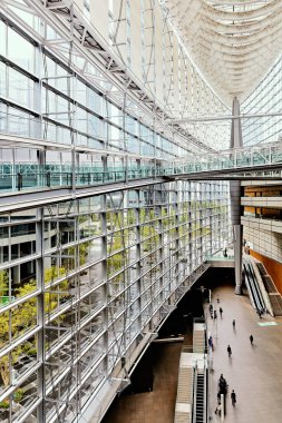 İnsanlar Tokyo 'daki Uluslararası Forum' a taşınıyor. Cam duvarlar modern tasarım ve doğal ışıkla çevrili..