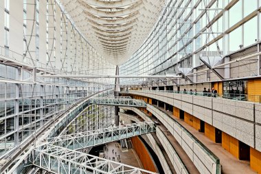 İnsanlar Tokyo 'daki Uluslararası Forum' dan geçiyor. Modern tasarımda cam duvarlar ve metal çerçeveler yer almaktadır. Ziyaretçiler mekanı keşfeder.