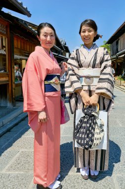 Güneşli bir günde Higashiyama, Kyoto 'da yürürken renkli kimono giyen iki kadın, yerel kültür ve manzaranın keyfini çıkarıyorlar..