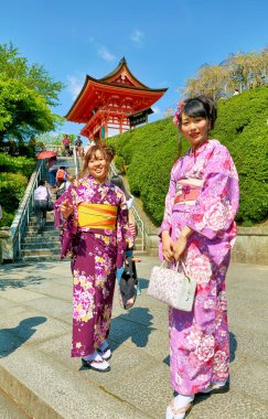 Kiyomizu Dera Tapınağı 'nda Koyasu Pagoda yakınlarında renkli kimonolu iki genç kadın duruyor. Kyoto 'nun bu açık gününde güneş parlıyor..