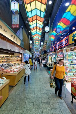 Ziyaretçiler Kyoto 'daki Nishiki Pazarı' nda yürüyorlar. Dükkanlarda taze yiyecekler ve yerel mallar sergileniyor.
