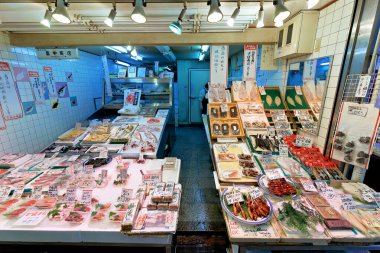 Bir balıkçı Kyoto 'daki Nishiki Market' te çeşitli deniz ürünleri satıyor. Müşteriler renkli tezgahları ve yerel sunumları keşfediyorlar.