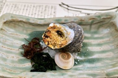 Miyajima, Hiroşima 'da yeşil bir tabakta salyangoz bulunan geleneksel Japon mutfağı servis edilir. Yerel yemeklere odaklandık..