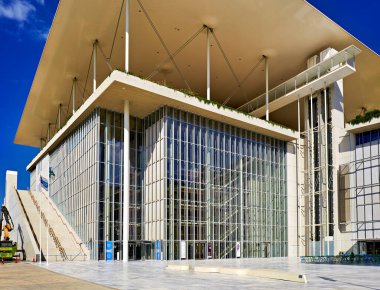 Ziyaretçiler Atina 'daki Stavros Niarchos Vakfı Kültür Merkezi' ni geziyorlar. Modern mimari açık mavi gökyüzüne karşı duruyor..