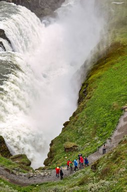Ziyaretçiler İzlanda 'nın güneybatısındaki Gullfoss şelalesi yakınlarındaki patikadan yürüyorlar. Su kayalıklardan aşağı akarak bölgede sis oluşturuyor..