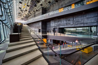 Ziyaretçiler, İzlanda 'nın Reykjavik kentindeki Harpa konser salonunun ana sahasında yürürken, gündüz vakti eşsiz mimariyi takdir ediyorlar..