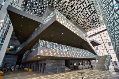 Ziyaretçiler Reykjavik, İzlanda 'daki Harpa konser salonunda yürüyorlar. Bina, gün ışığında benzersiz tasarımı ve modern mimarisini gösteriyor..