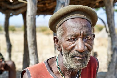 Namibya 'nın Kunene bölgesinde yaşlı bir adam duruyor. Zemba Bantu etnik grubundan ve düşünceli görünüyor..