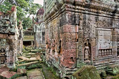 Antik Khmer tapınağı kalıntıları, muhtemelen Kamboçya 'daki Angkor Wat, karmaşık taş oymalar ve yosun kaplı bloklar, tarihi mimari sergileniyor..