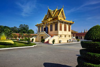 Ziyaretçiler, Phnom Penh, Kamboçya 'daki Kraliyet Sarayı' nın altın çatılı süslü sarı binasını keşfederek tarihi mimari ve bahçelerin keyfini çıkarıyorlar..