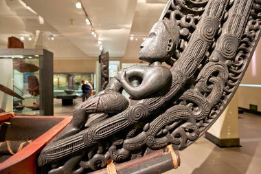 Ziyaretçiler Auckland Savaş Anıtı Müzesi 'ndeki Maori doğa tarihi galerisini keşfediyorlar. Oyma figürler ve kültürel eserler sergileniyor.