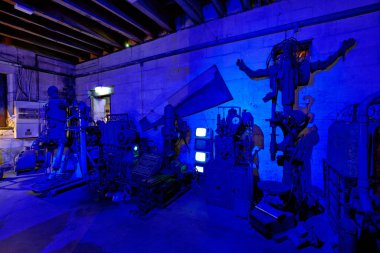 Ziyaretçiler, Oamaru 'daki Steampunk Karargahı' nda mavi ışıktaki garip makinelere bakıyorlar. Galeride eşsiz sanat eserleri ve montajlar yer alıyor..