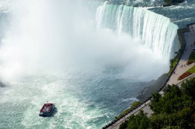Hornblower teknesindeki turistler ve yürüyüş yolu Kanada 'nın görkemli Niagara Şelalesi' nde güçlü doğal güzelliğin tadını çıkarıyorlar..