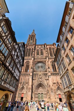 Turistler Alsace 'deki Strasbourg Katedrali' ni ziyaret ediyorlar. Yoğun caddeler ve tarihi binalar güneşli havanın tadını çıkaran ziyaretçilerle dolu..