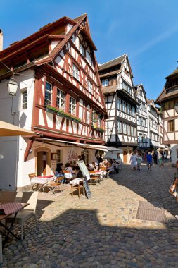 Ziyaretçiler Fransa 'da kaldırım taşı sokaklarda yürürken, diğerleri Strazburg' da kereste çerçeveli evlerin yakınındaki masalarda oturup yiyor ve içiyor..