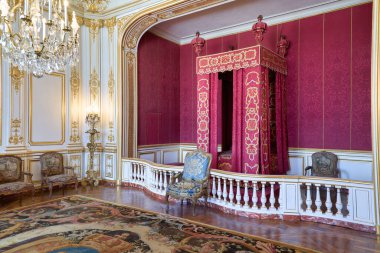 Ziyaretçiler, Chambord Şatosu 'nda kraliyet yatağı ve süslü tasarımı olan bir oda görebiliyorlar. Boşlukta zengin renkler ve ayrıntılı işçilik yer alıyor.