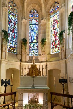 Ziyaretçiler, vitray pencereler ve sunağın yer aldığı Chenonceau Şatosu 'ndaki şapele bakıyorlar. Mimari tarihi tasarımı yansıtır..