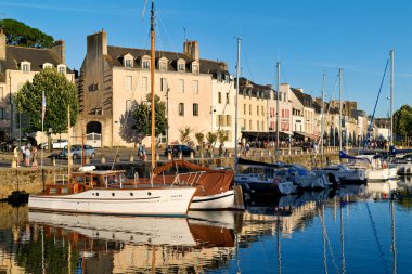 Tekneler Vannes limanına demirlediler. İnsanlar sahilde gezip güneşli havanın ve binaların manzarasının tadını çıkarıyorlar..