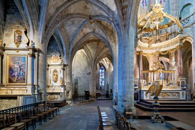 Ziyaretçiler Dinan 'daki Aziz Kurtarıcı Bazilikası' nın içini keşfediyorlar. Taş duvarlar ve kemerler dini mimari ve sanat eserlerini vurguluyor..
