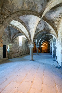 Ziyaretçiler Normandiya 'daki Mont Saint Michel Manastırı' ndaki Promenoir des Moines 'de yürüyorlar. İçerisi taş kemerler ve sessiz yollar gösteriyor..