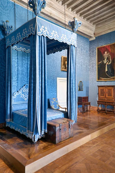 Ziyaretçiler Fransa 'daki Chateau de Chambord' un içinde mavi örtülü bir yatak görüyorlar. Oda sanat eserlerini de çerçeveletmiş..