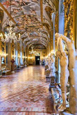 Ziyaretçiler Roma 'daki Doria Pamphilj Galerisi' ndeki sanat ve heykellere hayranlar. Salonda süslü dekorlar ve güzel avizeler var..
