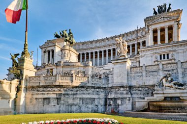 Turistler Roma 'daki Capitoline Hill' deki Victor Emmanuel Ulusal Anıtı 'nı keşfediyorlar. Güneş beyaz mimari ve heykellerin üzerinde parlıyor..