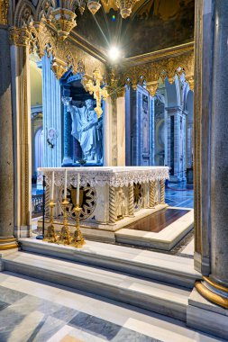 Archbazilica Katedrali 'nin içinde, ışık süslü bir sunağın üzerinde parlıyor. Mekanda mermer detaylar ve dini sanat eserleri var. Ziyaretçiler tasarıma hayran.