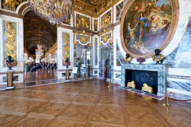 İnsanlar Versailles Sarayı 'nın büyük salonlarında yürürler. Ünlü sarayın içindeki sanat eserlerine ve mimarisine hayran kalırlar..