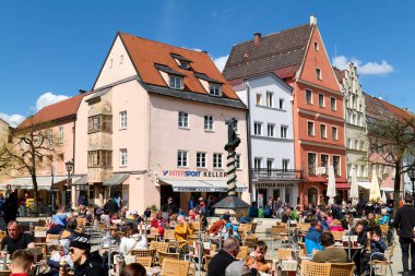 İnsanlar güneşli bir günde Fussen, Bavyera 'daki açık kafelerde yemek yemekten hoşlanırlar..