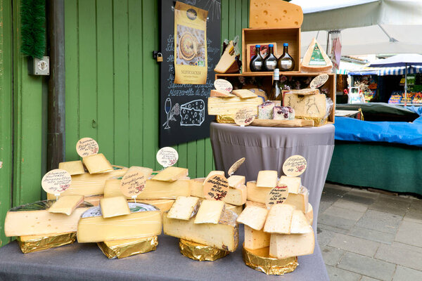 Visitors explore a variety of cheeses at Viktualienmarkt in Munich, Germany. Vendors showcase their products in an open market setting.