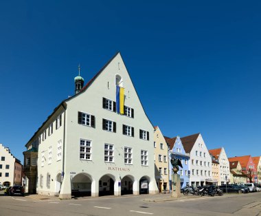 İnsanlar, Bavyera 'daki Romantik Yol boyunca uzanan tarihi bir yer olan Schongau' daki belediye binası yakınlarında toplanıyorlar. Parlak mavi gökyüzü sahneye ekleniyor.