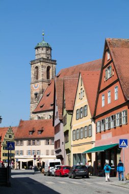 Ziyaretçiler, Romantik Yol 'daki eski Dinkelsbuhl kasabasında yürüyorlar. Tarihi binalar ve kule mavi gökyüzünün altında büyüleyici bir sahne yaratıyor..