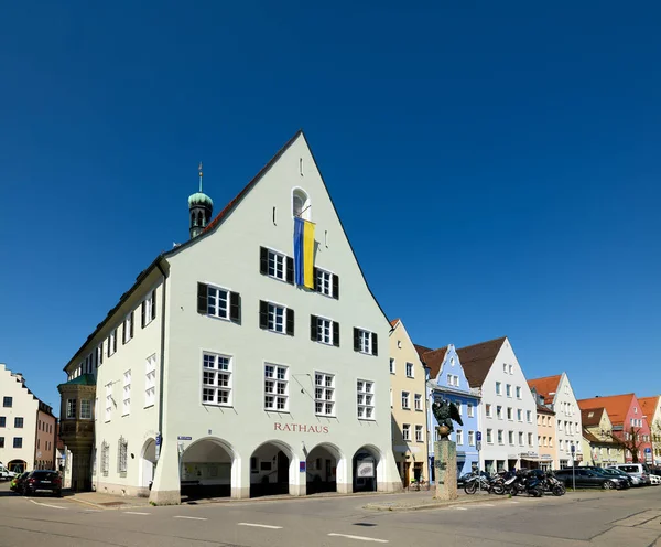 İnsanlar, Bavyera 'daki Romantik Yol boyunca uzanan tarihi bir yer olan Schongau' daki belediye binası yakınlarında toplanıyorlar. Parlak mavi gökyüzü sahneye ekleniyor.