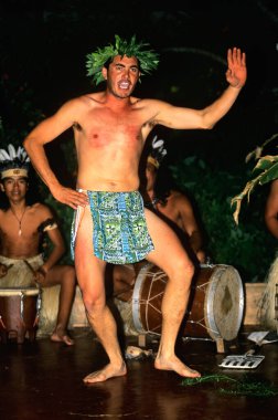 Yaprak taç giyen bir adam, Paskalya Adası 'ndaki bir gece etkinliğinde davulcuların çalması gibi enerjiyle dans eder. Kalabalık kültür gösterisinden hoşlanıyor.